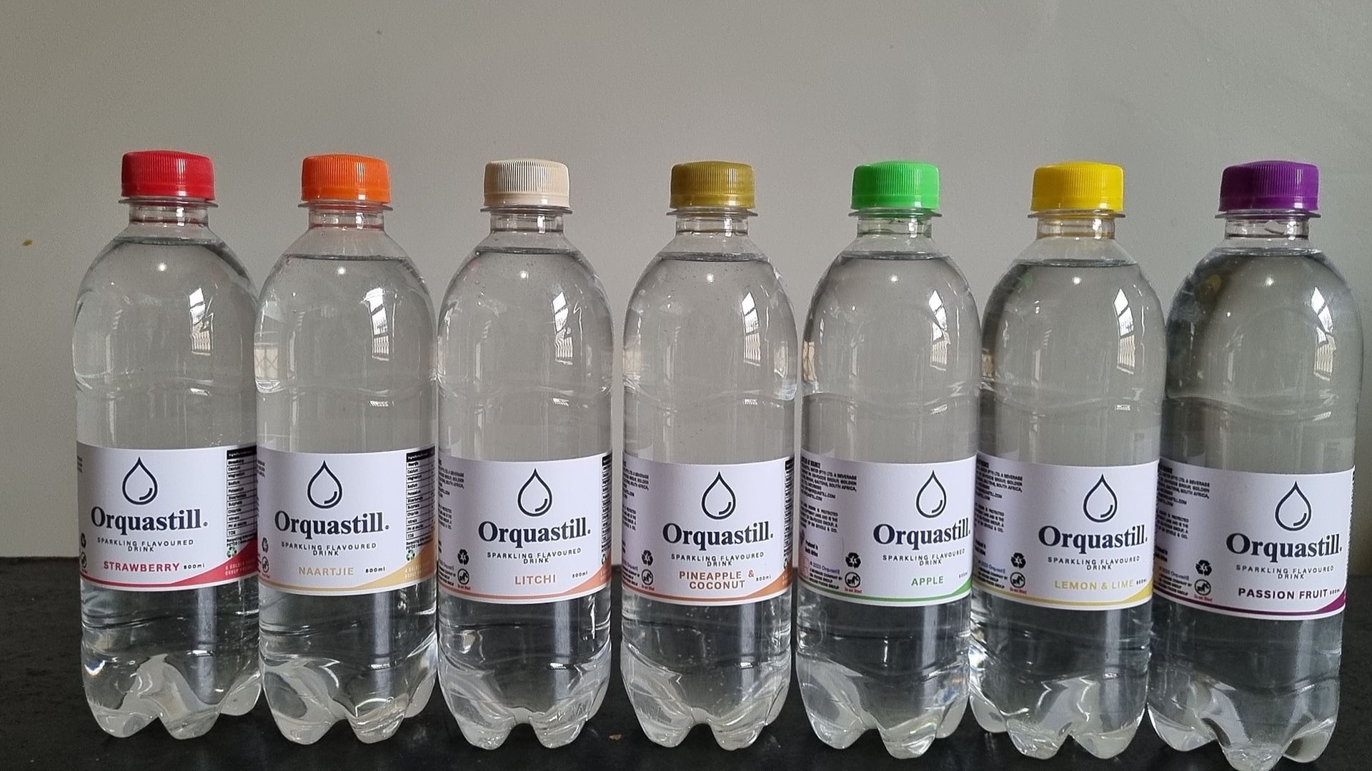 The seven Orquastill Infusions sparkling flavoured water bottles lined up